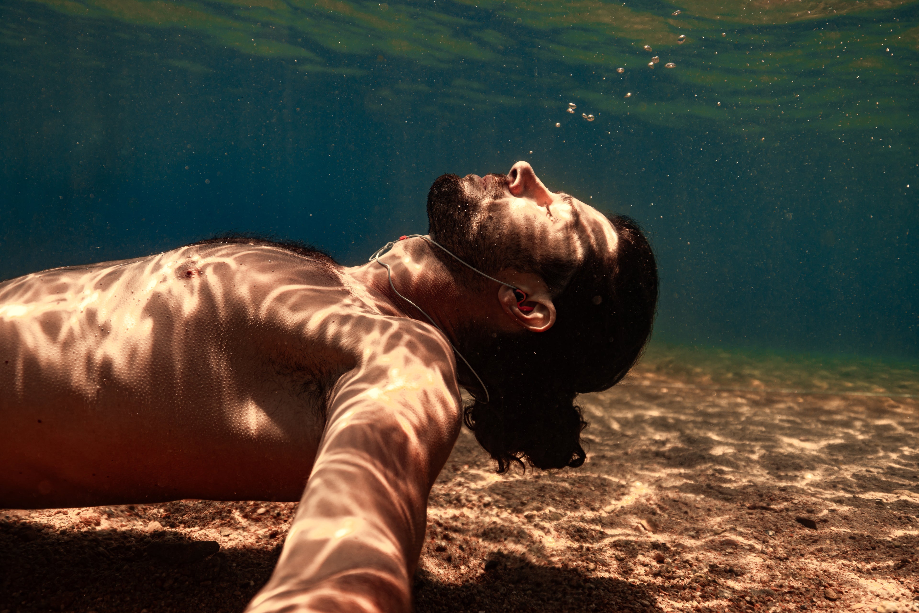 Giovanni Bianco performing underwater free diving techniques in the blue waters, focused on equalization and breath control.